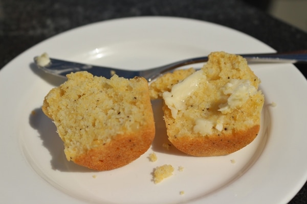 a halved corn muffin slathered with butter on a white plate