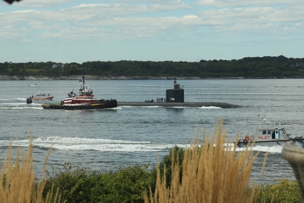 a submarine with people standing on top of it in the water