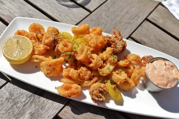 a white platter topped with fried calamari with sliced banana peppers