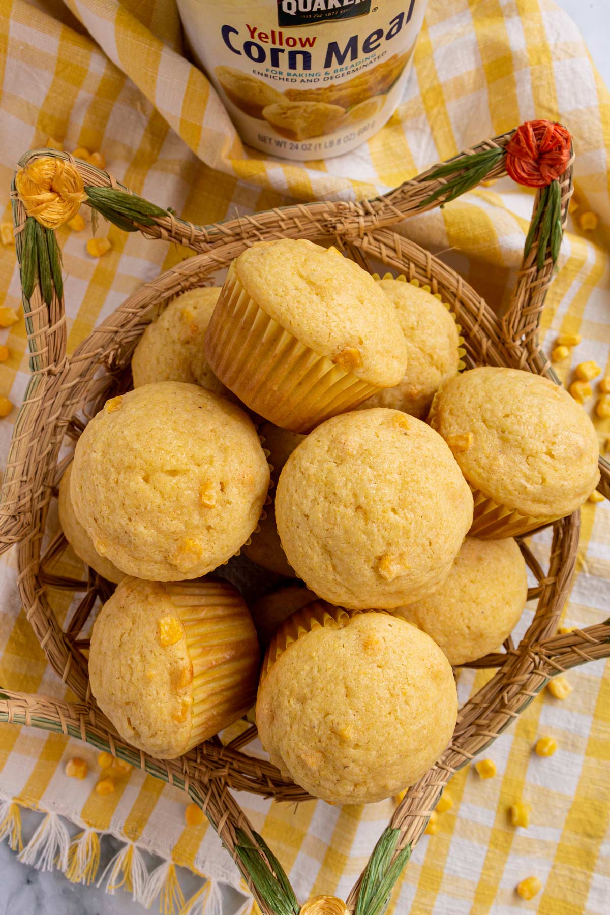 A basket of corn muffins on a yellow and white gingham towel. 