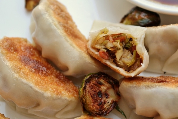 A closeup of a half-eaten brussels sprouts and bacon dumpling on a white plate