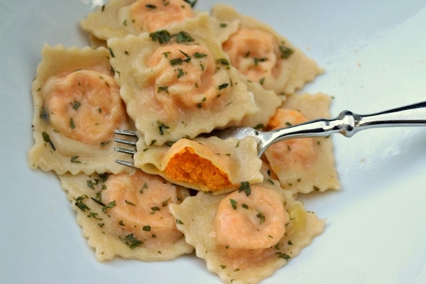 a plate of carrot ravioli with one cut open to show the orange-colored filling