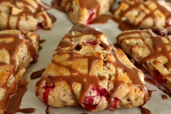 A closeup of a tray of cranberry apple scones topped with cinnamon glaze