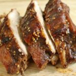 sliced baby back ribs with hoisin sesame sauce leaning against each other on a wooden board