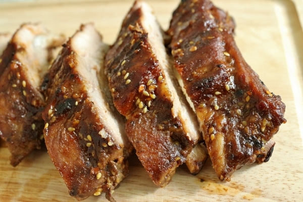 sliced baby back ribs with hoisin sesame sauce leaning against each other on a wooden board