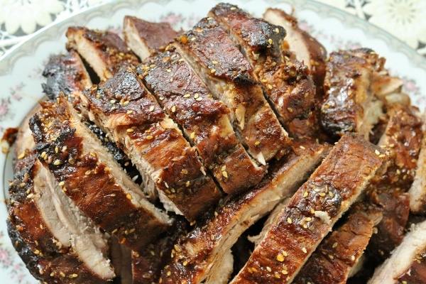 a pile of sliced baby back ribs with sesame seeds on a serving platter