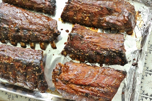 overhead view of a baking sheet of cooked baby back rib racks