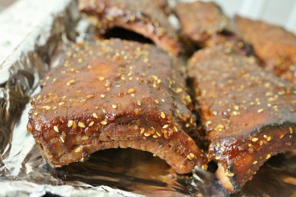 A closeup side view of cooked racks of baby back ribs with a sesame barbecue sauce