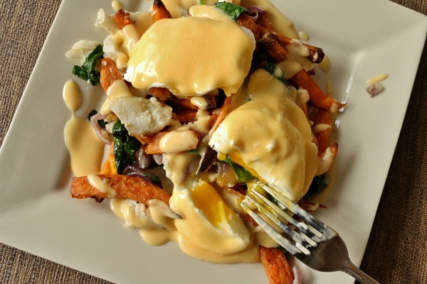 overhead view of a colorful plate of fish hash with poached eggs, with one cut open