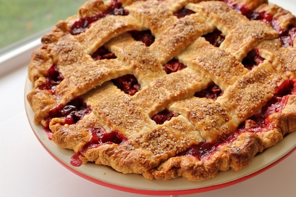 a lattice topped pie with bubbly red filling peeking out
