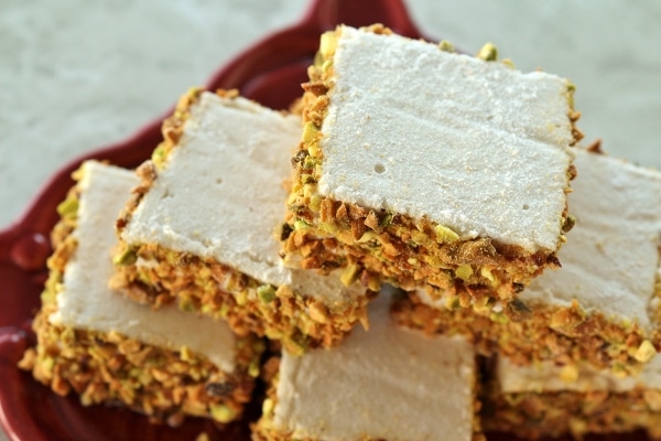a closeup of a stack of square marshmallows coated with chopped pistachios