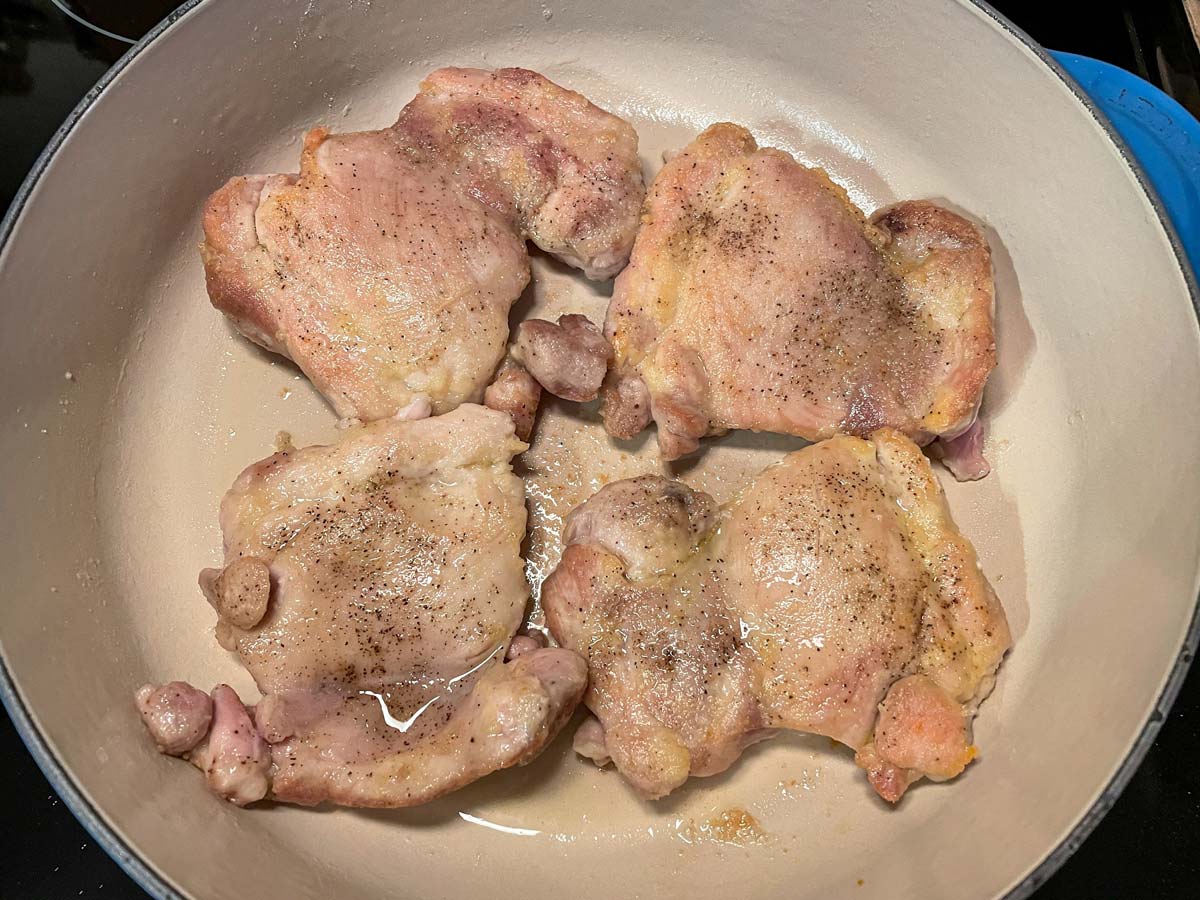 Seared boneless skinless chicken thighs in an enameled cast iron pan.