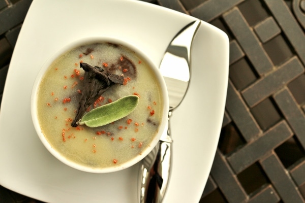 overhead view of a white ramekin topped with hardened clarified butter, mushroom, and sage leaf