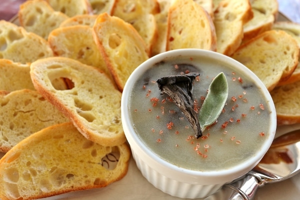 A platter of toasted baguette slices with a ramekin of pate on the side