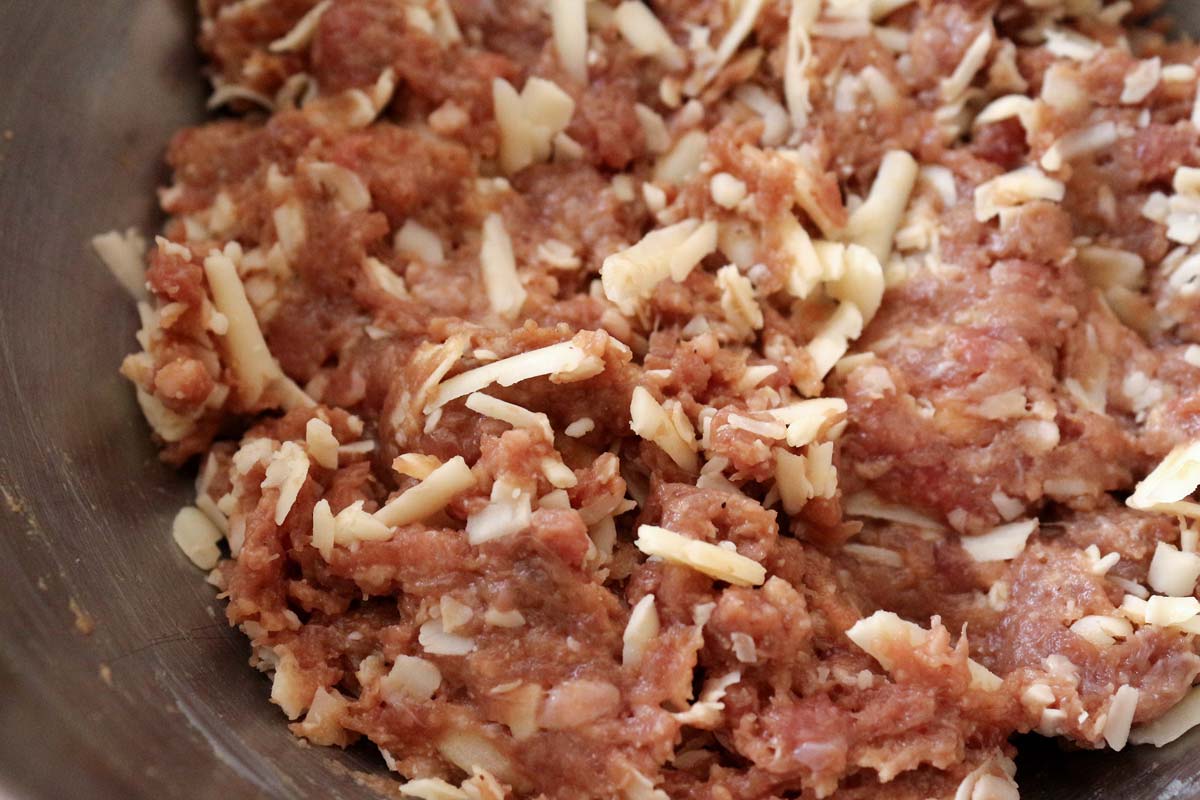 A combination of ground beef and shredded cheese in a mixing bowl.