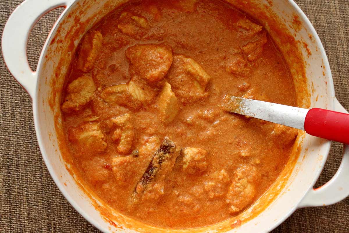 A pot of murgh masala chicken curry with a cinnamon stick on the surface.