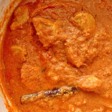 overhead view of a pot of creamy Indian chicken curry with a visible cinnamon stick