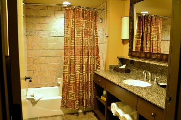 a hotel bathroom with a tub, sink and mirror