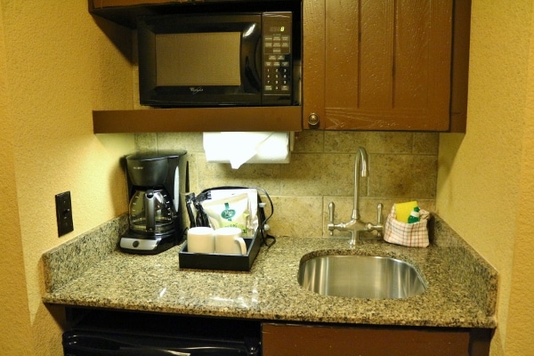 A kitchenette with a sink, coffee maker, and microwave