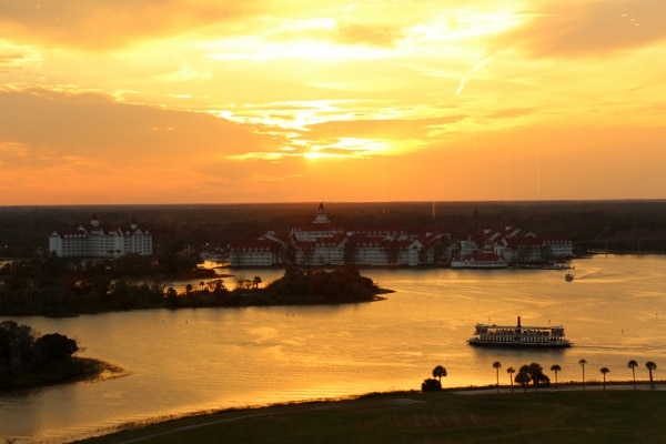 A sunset over a lagoon with Disney\'s Grand Floridian Resort in the distance