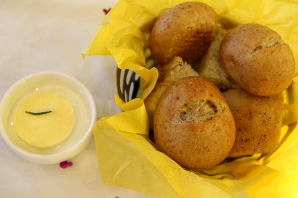 a bread basket with rolls and a serving of butter on the side