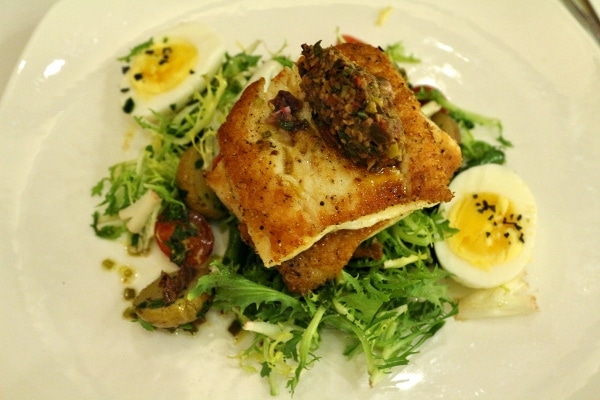 a plate of fish fillets served with greens and hard-boiled eggs