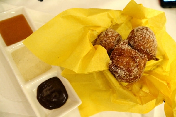 a basket of fried fritters served with a variety of dipping sauces