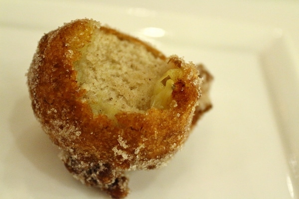 A half eaten fried fritter on a white plate