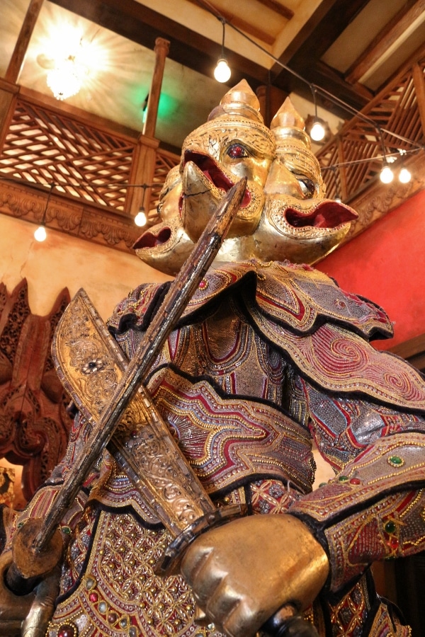 a statue of an Asian warrior with a golden head and big swords