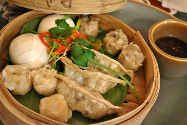 A bamboo steamer basket filled with a variety of Asian dumplings