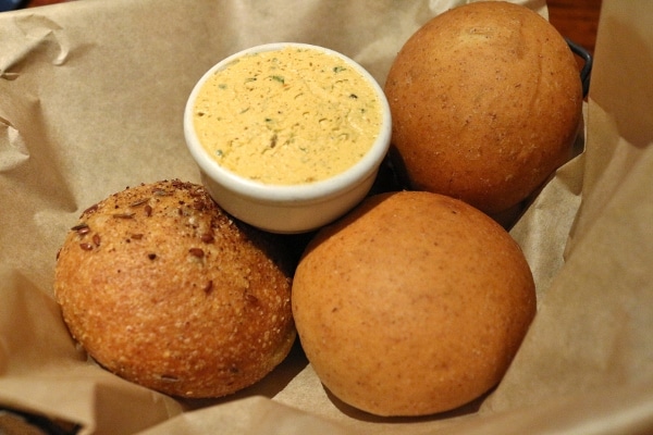 A closeup of a bread basket with rolls and herbed butter