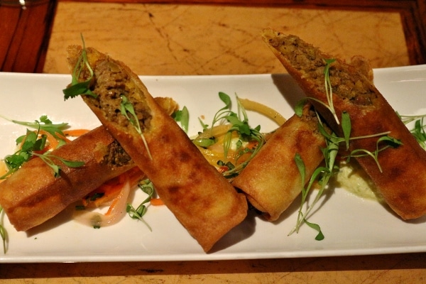 two crispy spring rolls cut in half and arranged artfully on a white plate