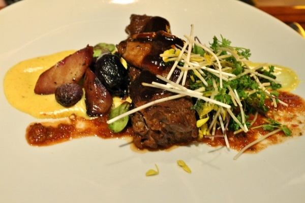 A plate of beef short ribs with mushrooms and greens