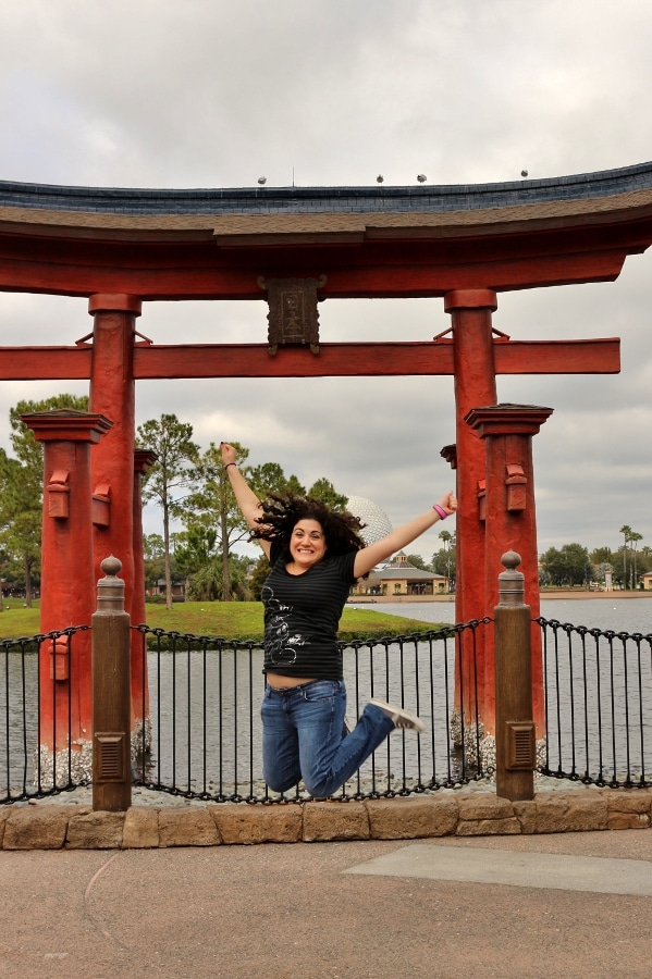 a woman jumping in front of a Japanese arch in Epcot\'s Japan Pavilion