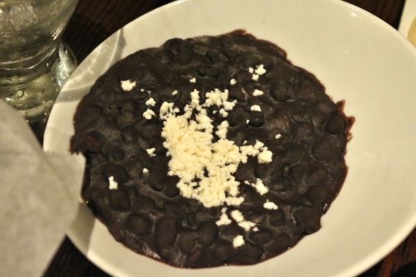 A bowl of stewed black beans topped with crumbled white cheese