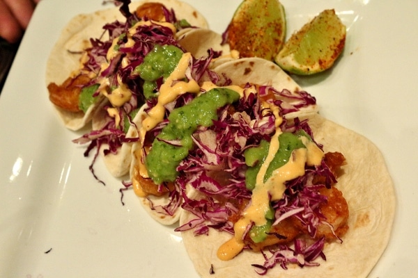 a plate of three fried shrimp tacos with red cabbage slaw