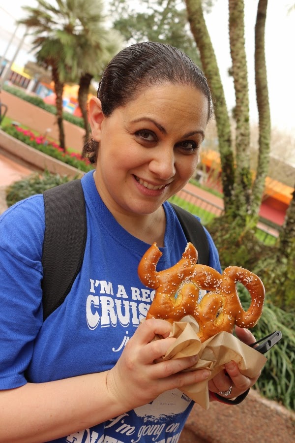 a woman eating a Mickey Mouse shaped pretzel