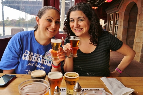 two women posing with small glasses of beer from their beer flight