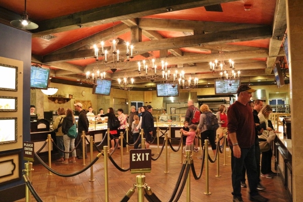 A group of people standing in line inside Les Halles in Epcot\'s France Pavilion