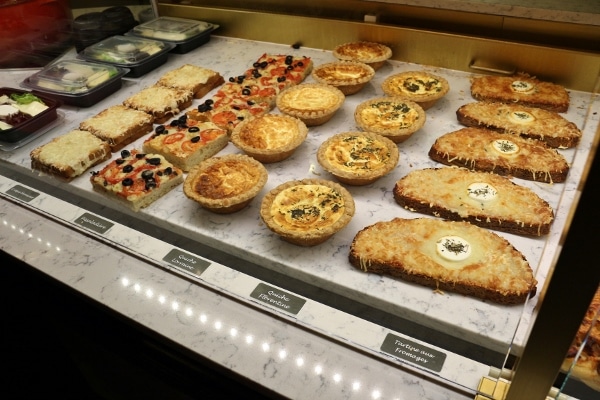 rows of small quiches and sandwiches in a display case