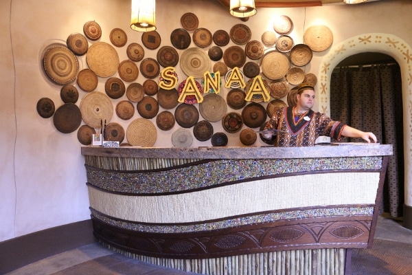 a man standing in front of a sign that says Sanaa