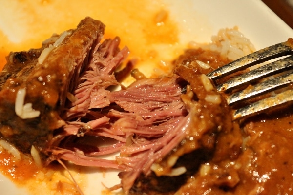 a closeup of a piece of tender beef short rib torn with a fork