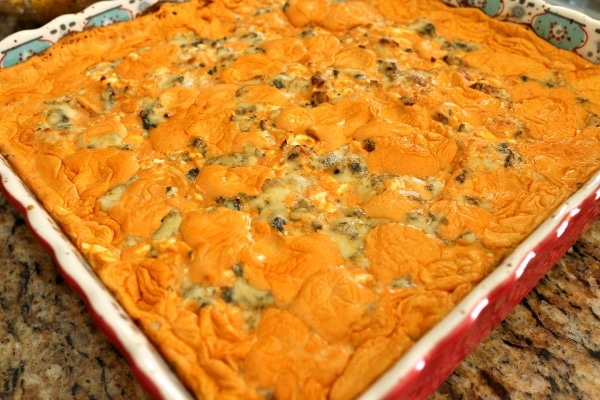 a bubbly dish of buffalo chicken dip with crumbled blue cheese on top