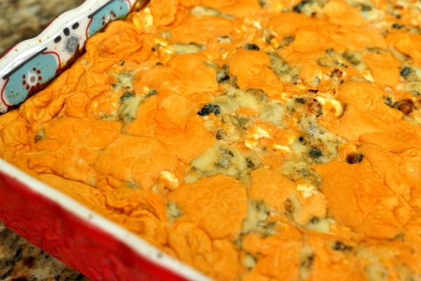 A closeup of bubbly and cheesy buffalo chicken dip in a square baking dish