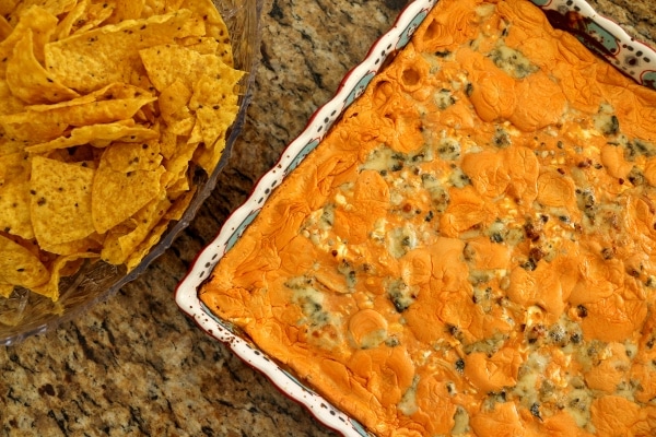 overhead view of a square baking dish of buffalo chicken dip with chips on the side