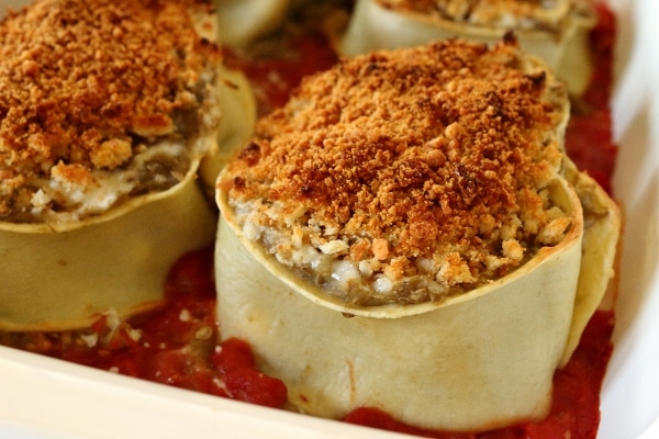 A closeup of a baking dish of eggplant and parmesan rotolo topped with bread crumbs