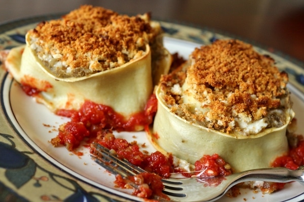 a side view of a plate of eggplant rotolo with tomato sauce and a fork