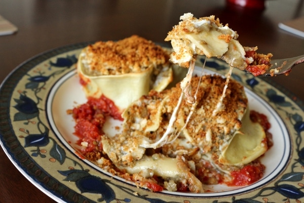 a forkful of pasta lifting up from a plate with strings of melted cheese