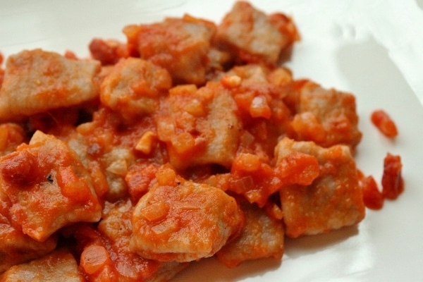 a closeup of gnocchi al sagrantino all\'amatriciana on a white plate