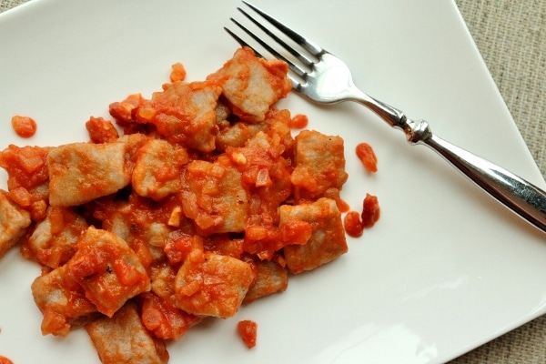 overhead view of a plate of gnocchi with a chunky tomato and meat sauce